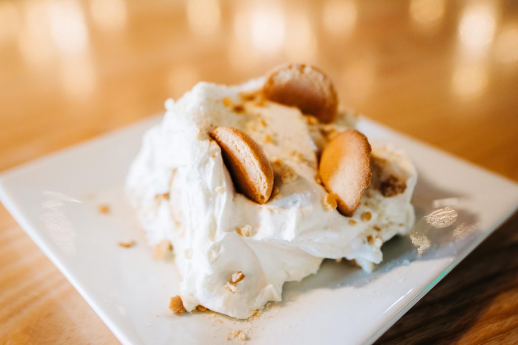 a picture of banana pudding topped with whipped cream and vanilla wafers on a plate