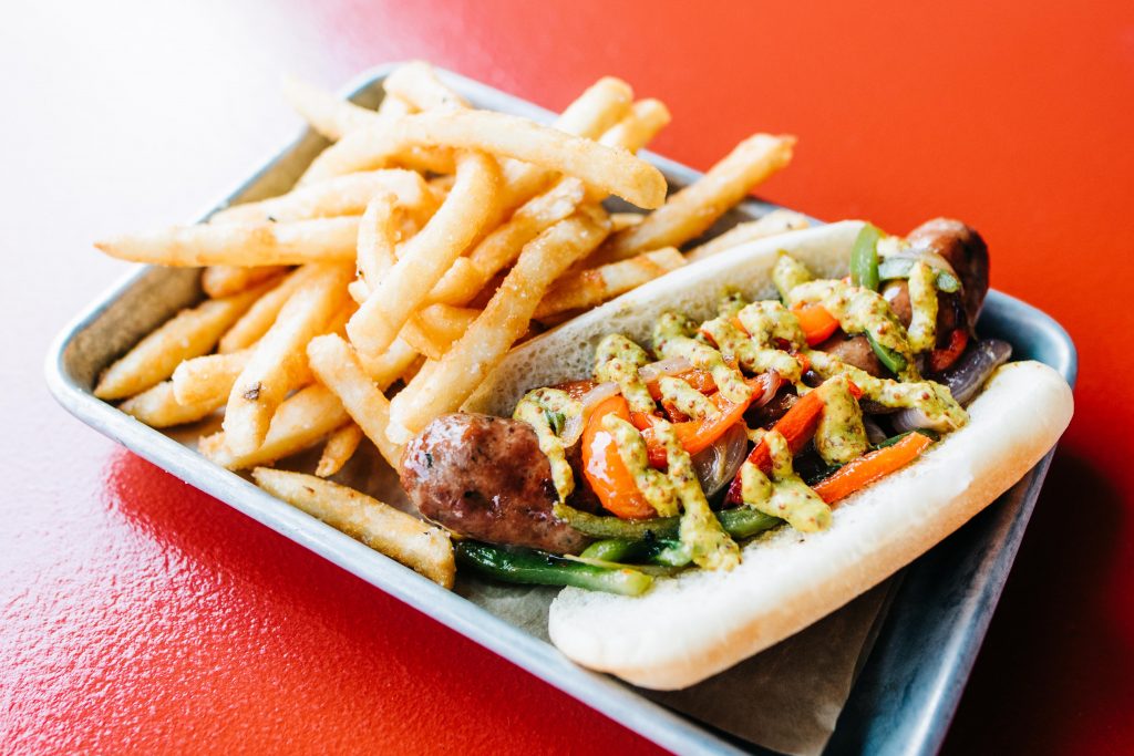 a picture of a smoked sausage with onions, peppers, and beer mustard served with fries on a plate